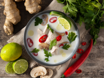 Traditional Thai food Tom Kha Gai in bowl on wooden table